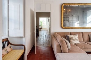 Ein Flur mit einer Holzbank, einem beigen Sofa und einem Spiegel an der Wand.
