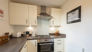 A modern kitchen with white cabinets, a gas stove, an oven, and a toaster. - Host Stay The Sanctuary (Whitby)