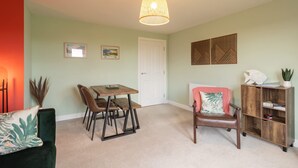 A dining area with a table and chairs, a bookshelf, and a door. - Host Stay The Sanctuary (Whitby)