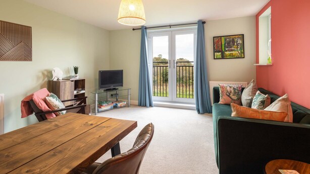 A living room with a wooden dining table, a TV, and a sofa. - Host Stay The Sanctuary (Whitby)