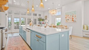 Una cocina amplia con una isla grande, luces colgantes y vistas al exterior.