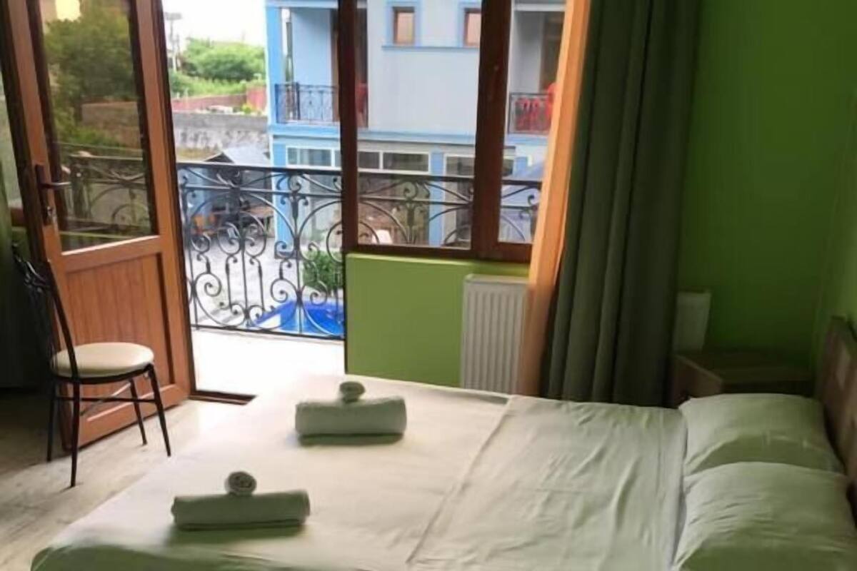 A hotel room with a bed, a chair, and a view of the outside.
