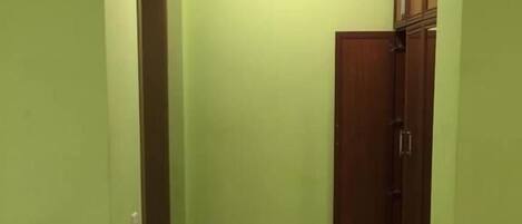 A room with green walls, a wooden floor, and a ceiling light.