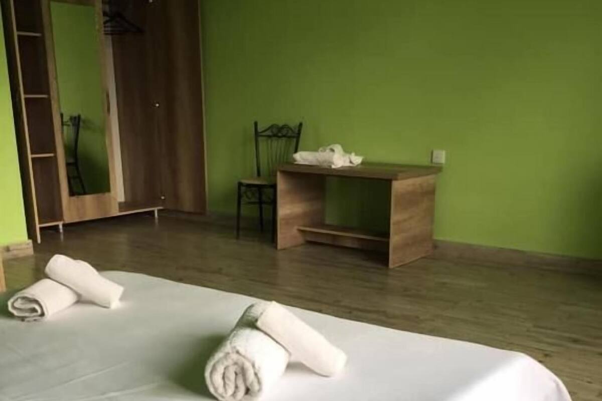 A room with two beds, a wooden desk, a chair, and a wardrobe.