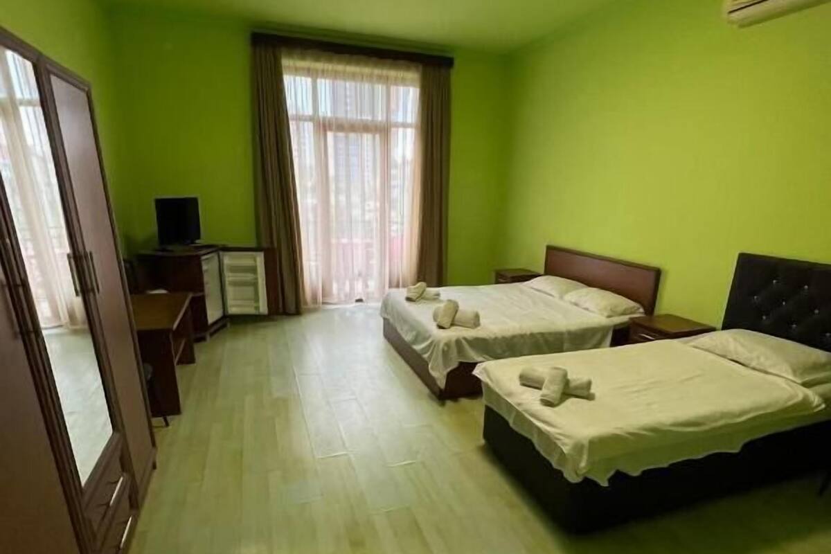 A hotel room with two beds, a desk, a television, and a window with curtains.