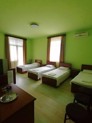 A hotel room with four single beds, a desk with a chair, and a TV. - MARETI HOTEL (Batumi)