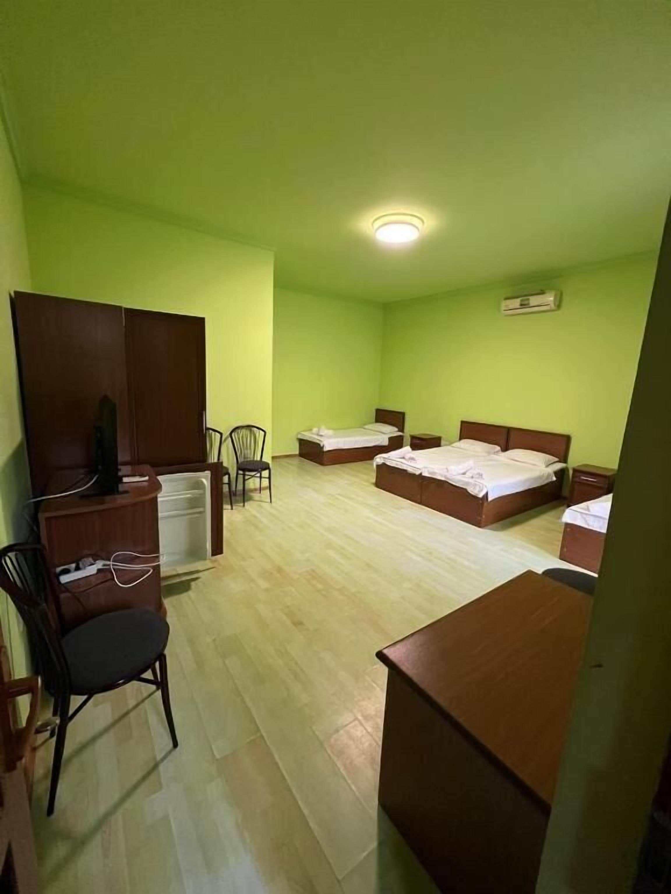A room with two beds, a desk, a chair, and an air conditioning unit.