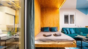 Ein gemütliches Schlafzimmer mit einem hölzernen Bett, einem grünen Sofa und einem kleinen Tisch mit einer Vase.