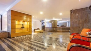 Un hall d’hôtel moderne comprenant un comptoir d’accueil, un espace salon et un mur décoratif.