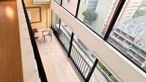 Un appartement moderne doté d’un balcon, de grandes fenêtres et offrant une vue sur les bâtiments environnants.