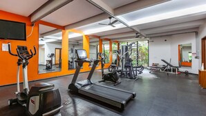 Une salle de sport équipée de tapis de course, de vélos elliptiques et de matériel de musculation.
