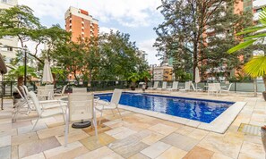 Una piscina all'aperto con lettini da relax e solarium piastrellato.