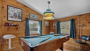 A pool table in a room with wooden walls, a ceiling fan, and a framed picture on the wall. - New Listing! Hot Tub, Foosball, Fireplace, Pool Table, & Free Attractions! (Sevierville)