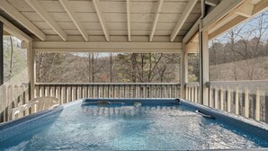 A hot tub under a covered area with a view of trees. - New Listing! Hot Tub, Foosball, Fireplace, Pool Table, & Free Attractions! (Sevierville)