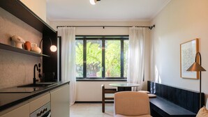 A modern kitchen with a dining area, a bench, and a window with curtains. - Liiiving in Porto - Casa Duque Apartment I (Porto)