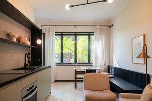 A modern kitchen with a dining area, a bench, and a window with curtains. - Liiiving in Porto - Casa Duque Apartment I (Porto)