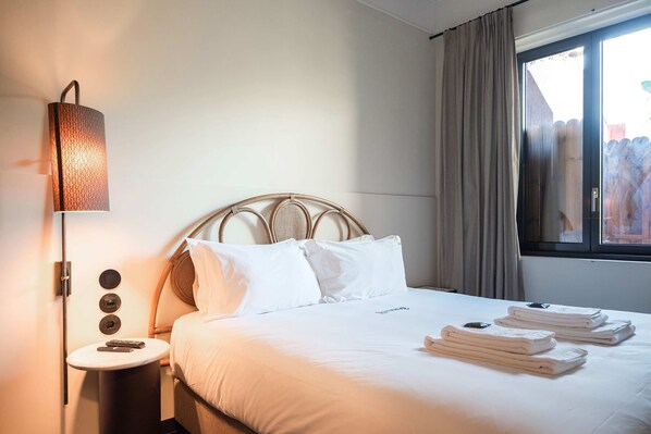 A neatly made bed with white linens, a bedside lamp, and a window with curtains. - Liiiving in Porto - Casa Duque Apartment I (Porto)