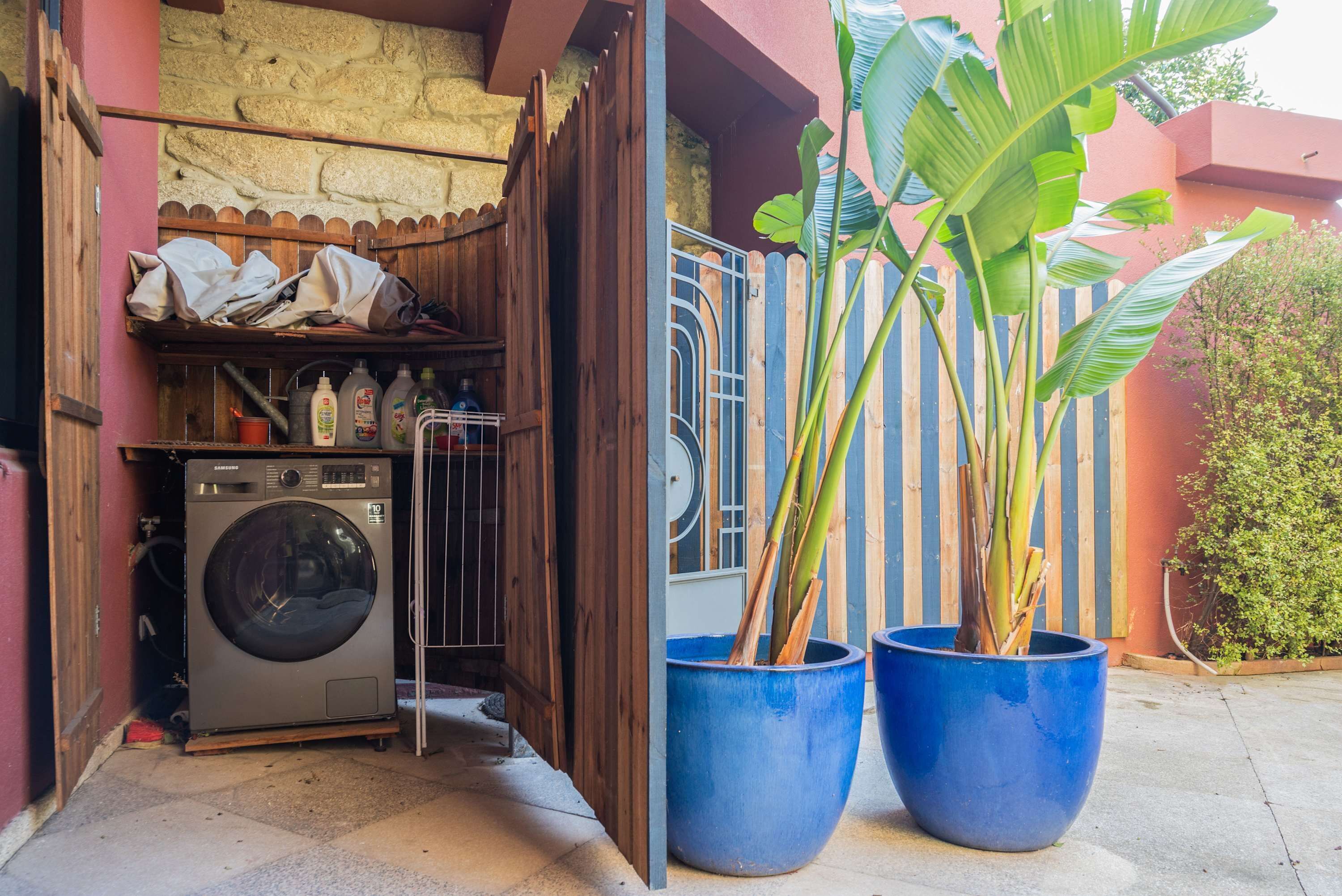 A laundry area with a washing machine, a drying rack, and a potted plant.
