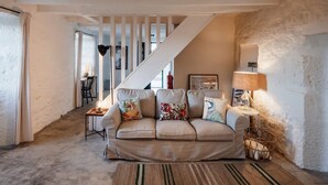 A cozy living room with a sofa, a lamp, and a staircase. - Liiiving in A Ores - Ocean View House (Sao Roque do Pico)