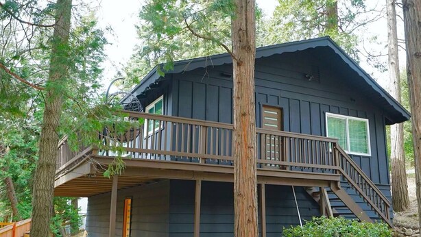 A two-story cabin with a balcony, surrounded by trees. - Beautiful Renovated Cozy Forest Home in Crestline with Hot Tub (Crestline)