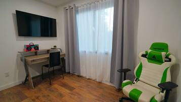 A room with a desk, chair, and a gaming chair.