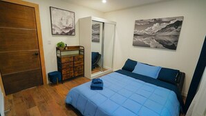 A bedroom with a bed, a wardrobe, a dresser, and two wall-mounted paintings. - Beautiful Renovated Cozy Forest Home in Crestline with Hot Tub (Crestline)