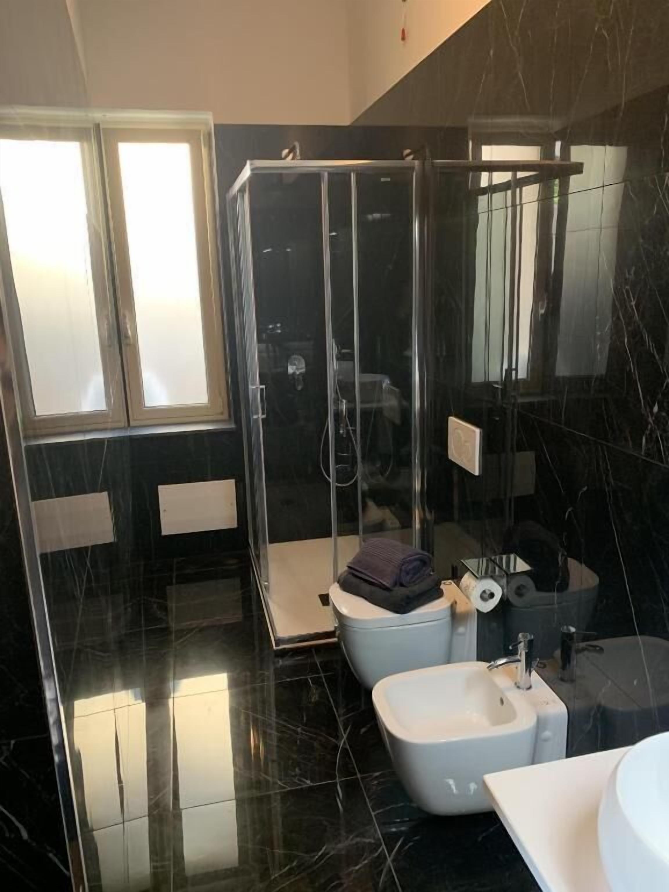 Ein modernes Badezimmer mit einer gläsernen Duschkabine, einer Toilette und einem Waschbecken.