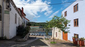 A narrow street with cobblestone pavement, parked cars, and buildings with balconies and windows. - Unusual House (Porto)