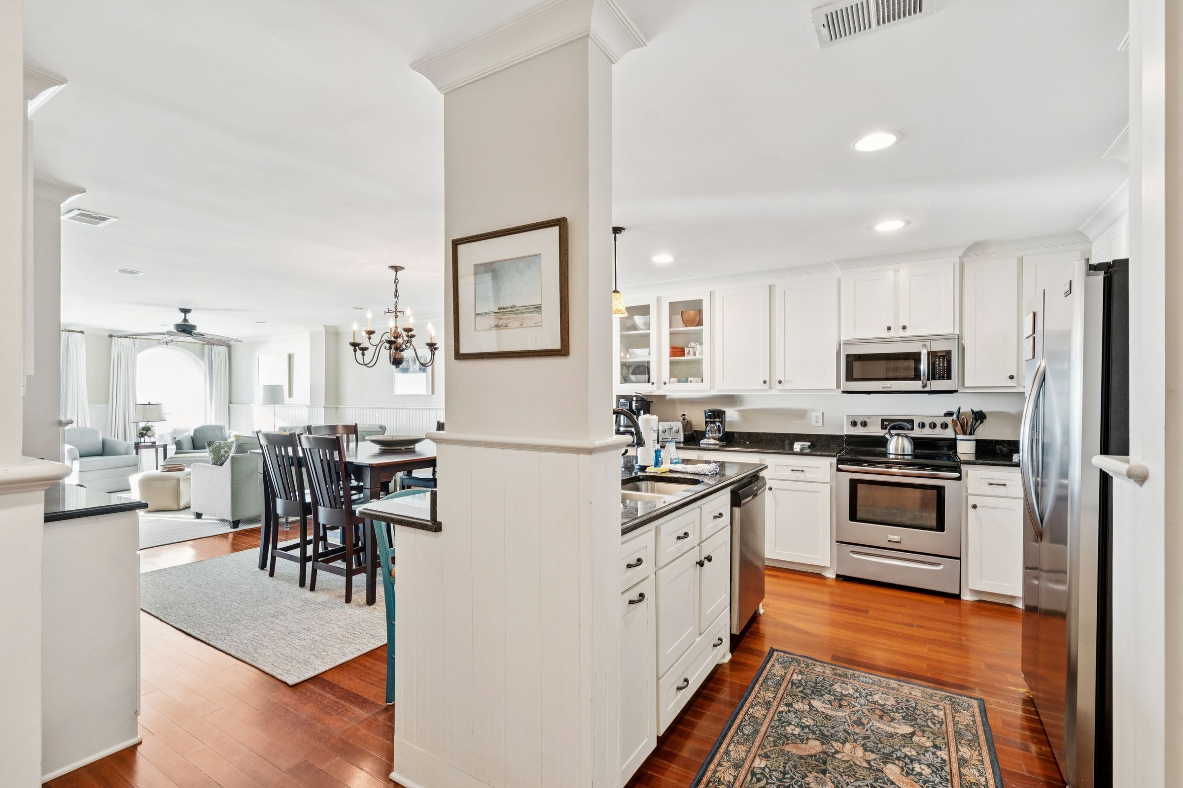 A modern kitchen with white cabinetry, stainless steel appliances, and a dining area with a chandelier.