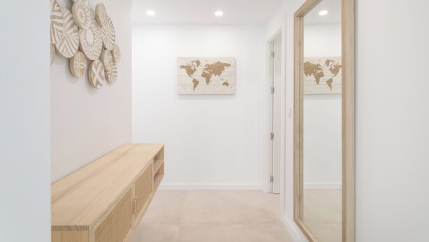 Een hal met een houten bankje, een wereldkaart als kunstwerk, en een spiegel aan de muur.