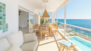 Un balcon avec une table et des chaises pour prendre les repas, une piscine et une vue sur la mer.