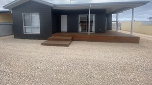 A modern two-story house with a covered porch, a front door, and a large sliding glass door. - Lofty's Shack - Modern 3 bedroom, Free WiFi!, Off peak special! (Edithburgh)