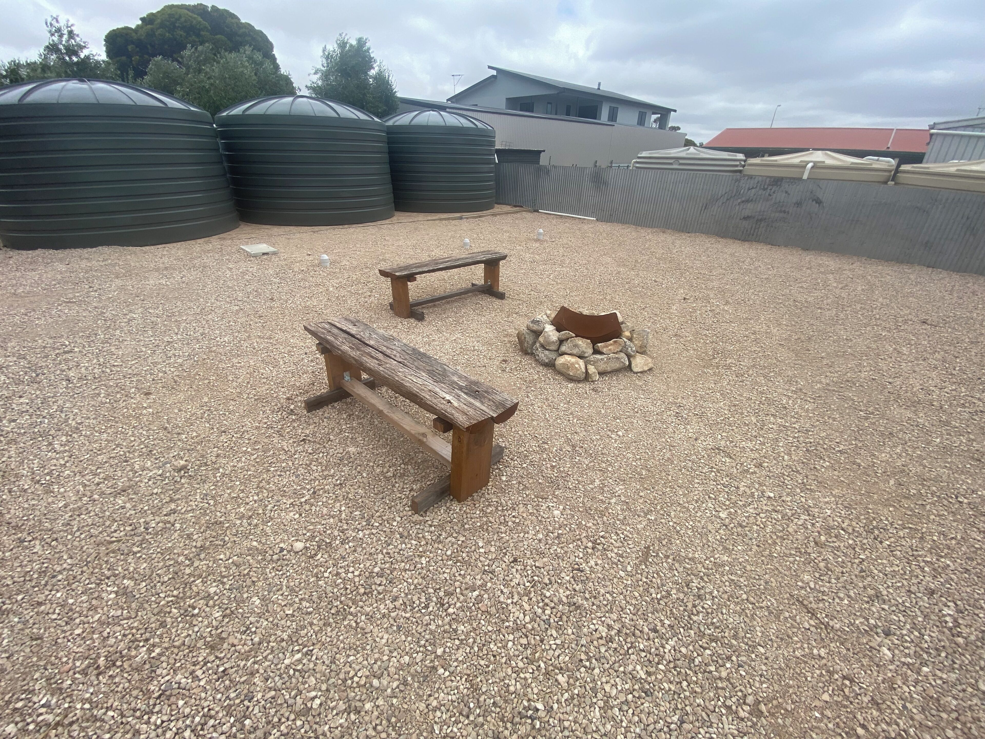 Zona de grava con dos bancos de madera y un pequeño montículo de piedras.