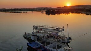 A docked boat at sunset with calm water and a distant shoreline.