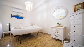 Une chambre à coucher comprenant un lit, une commode, un miroir et un climatiseur fixé au mur.