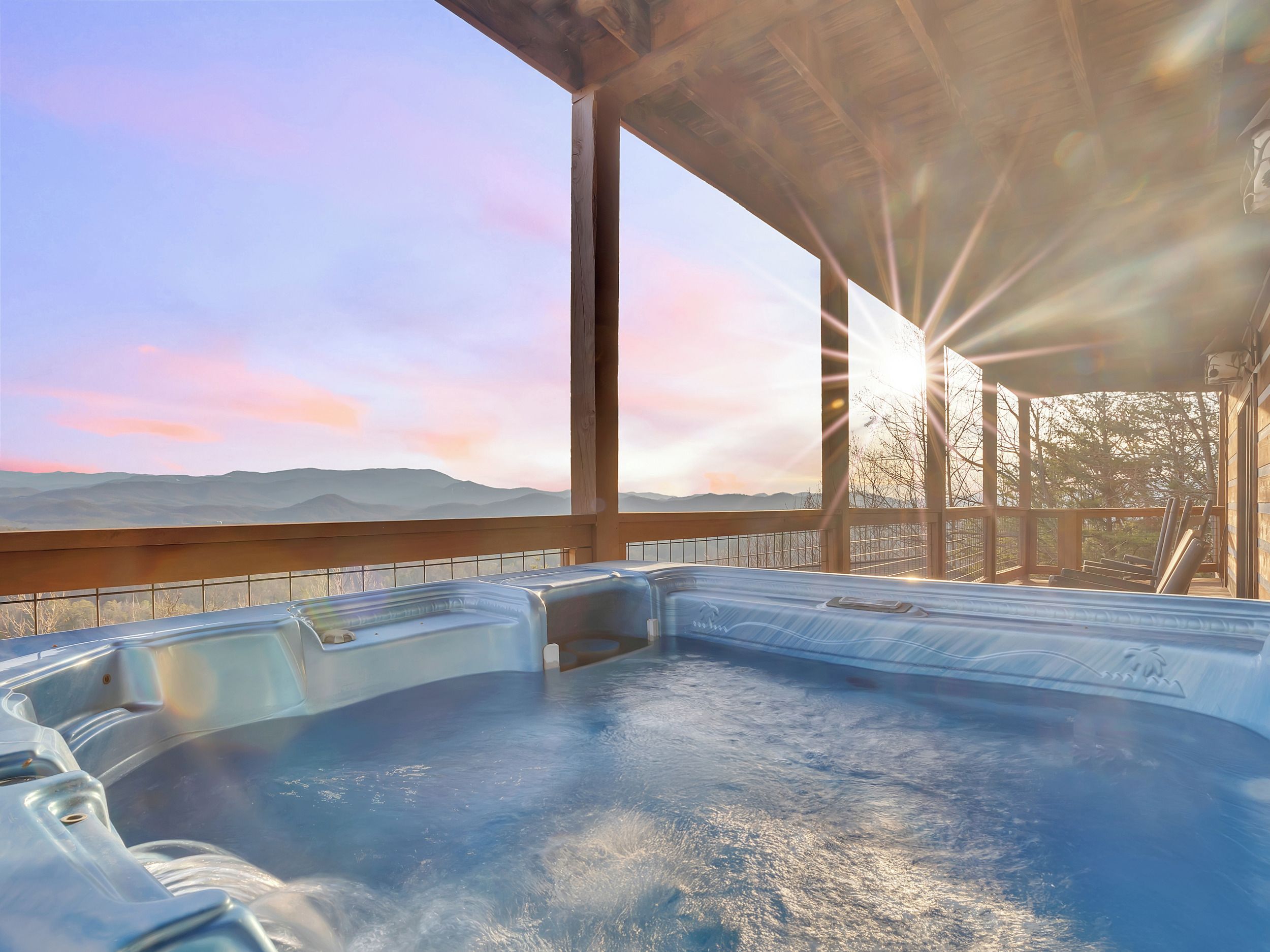 A hot tub area with a view of mountains and a sunset.