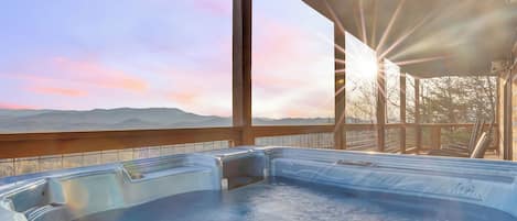 A hot tub area with a view of mountains and a sunset.