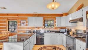 Una cocina moderna con paredes de madera, armarios blancos, una isla grande y una lámpara colgante.