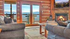 Una sala de estar acogedora con sofás de cuero, una chimenea y un ventanal con vistas panorámicas.