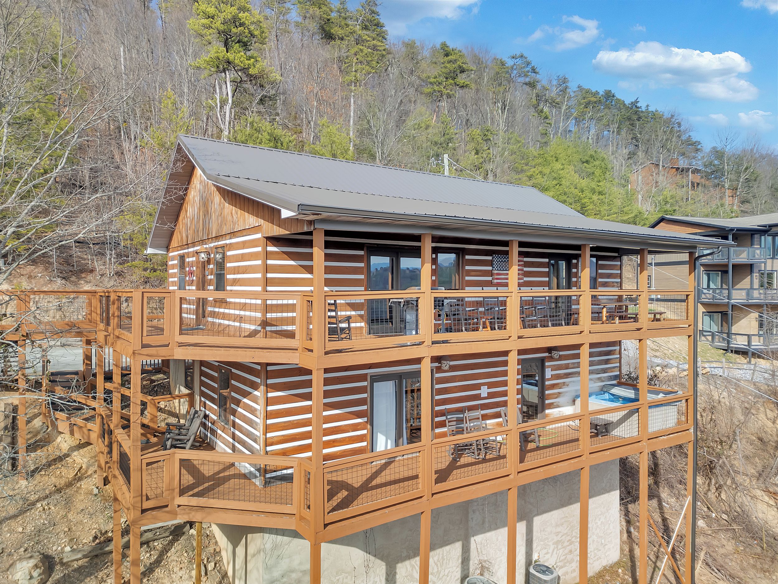 A two-story log cabin with a balcony and a deck.