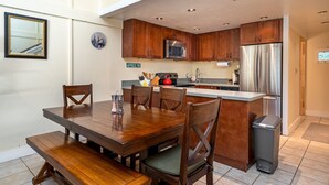 Une cuisine compacte dotée de meubles en bois, d’un réfrigérateur en acier inoxydable et d’un coin repas avec une table et des chaises en bois.