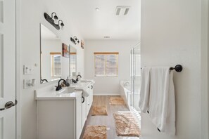 A modern bathroom with white fixtures, a large mirror, and a walk-in shower. - Charming Pet-friendly Getaway In Sunny Beaumont 4 Bedroom Home (Beaumont)
