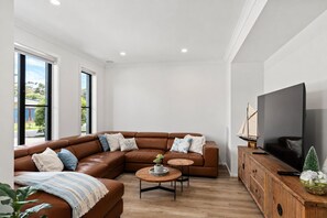 A modern living room with a sectional sofa, a coffee table, a TV, and a wooden cabinet. - Beach Bliss by Ready Set Stay (Cowes)