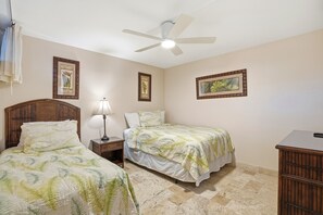Quarto com duas camas, um ventilador de teto e quadros nas paredes.