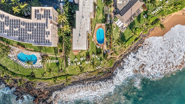 An aerial view of a coastal hotel with multiple swimming pools, a beach, and a rocky shoreline. - Kamaole Nalu, #304 2 Bedroom Condo (Kihei)