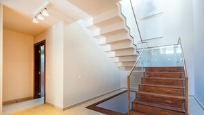 A modern staircase with glass railings and wooden steps, leading to an upper floor.