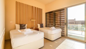 A hotel room with two beds, a large sliding glass door to the balcony, and a wooden slat wall.