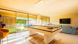 A modern living room with a pool table, a sofa, and a TV.
