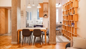 A modern kitchen with a dining area, wooden columns, and a built-in bookshelf. - Historic 2BR Oasis in Kolonaki (Athina)