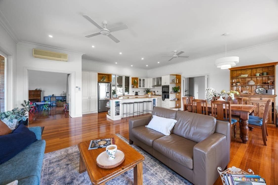 A spacious living area with a leather sofa, a coffee table, and a dining table with chairs.